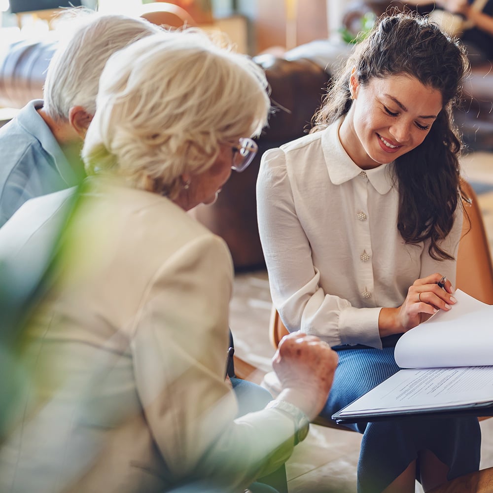 Funeral professional reading documents to senior couple in a casual environment.