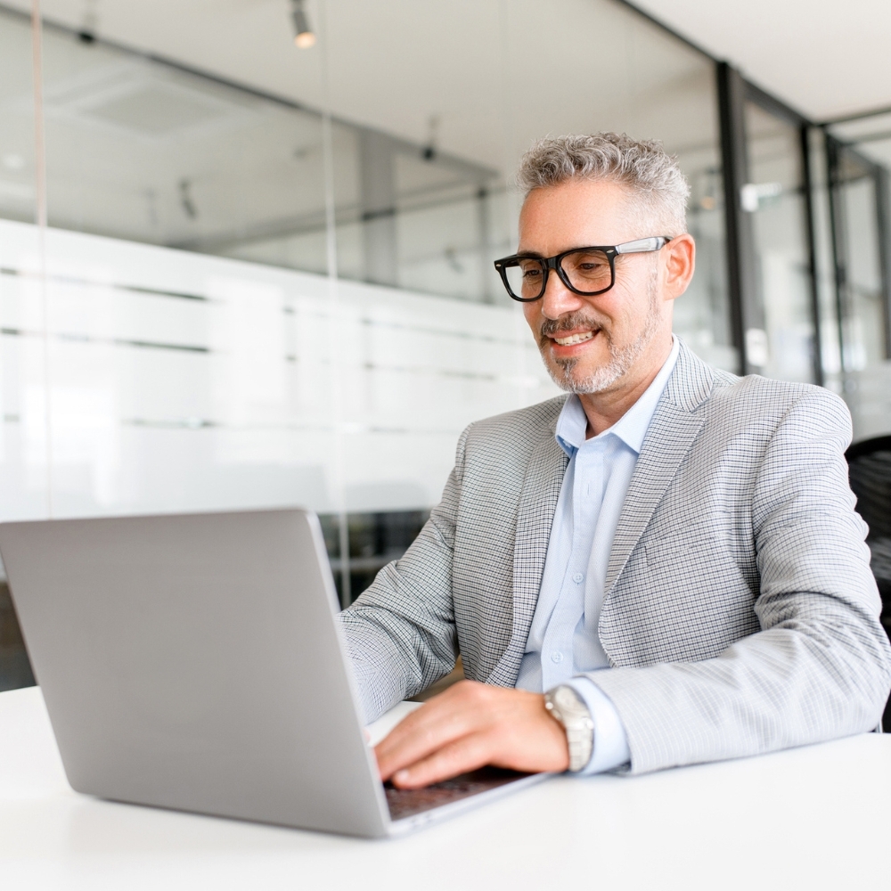 A businessman typing on a laptop while sitting at his desk.